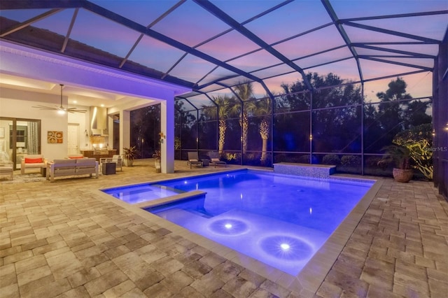 pool at dusk with an outdoor hangout area, a lanai, a patio, ceiling fan, and an in ground hot tub