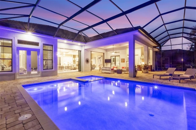 pool at dusk featuring a lanai, outdoor lounge area, and a patio area