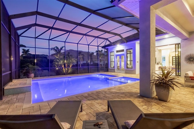 pool at dusk featuring a lanai, a patio, french doors, and an in ground hot tub