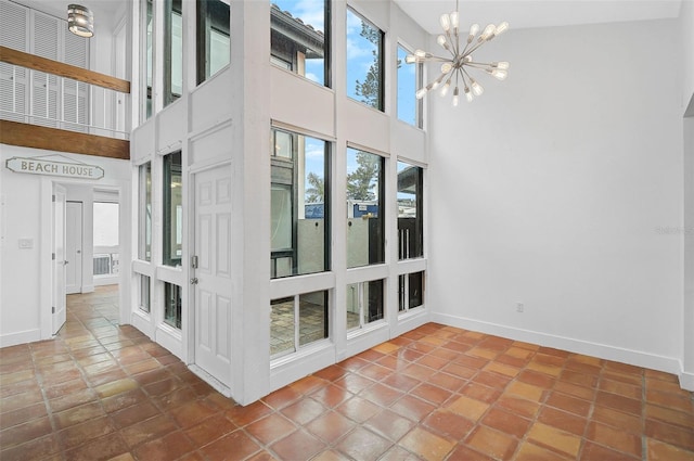 interior space with a chandelier, a towering ceiling, tile patterned floors, and a wealth of natural light