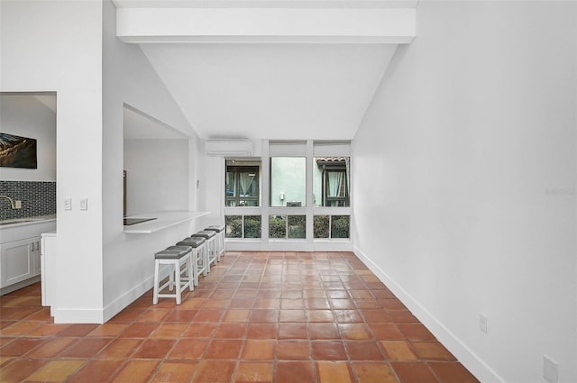 interior space featuring vaulted ceiling with beams, light tile patterned floors, a sink, and baseboards