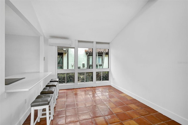 interior space featuring a wall mounted AC, tile patterned floors, and baseboards