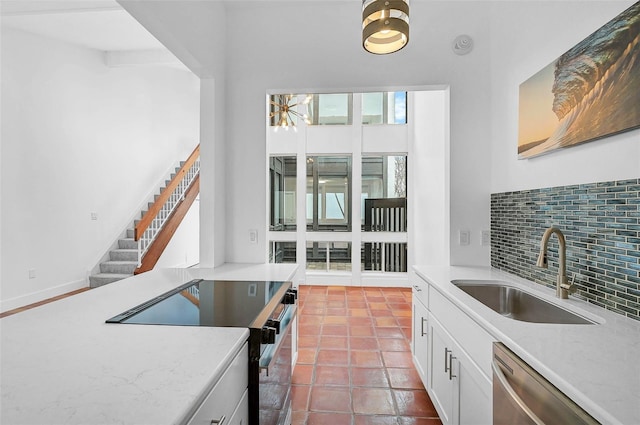 kitchen featuring light stone counters, a sink, white cabinets, appliances with stainless steel finishes, and decorative backsplash