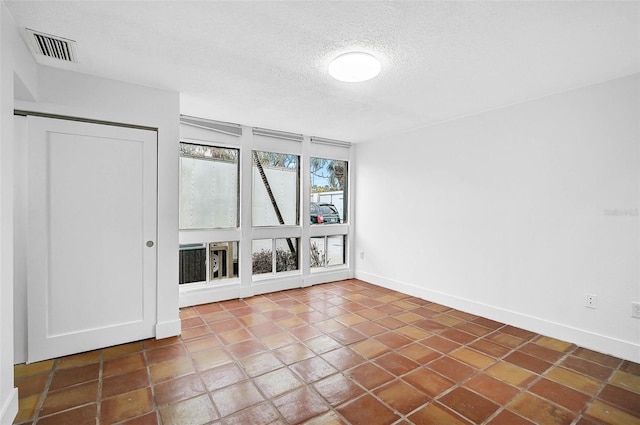 unfurnished room with baseboards, visible vents, and a textured ceiling