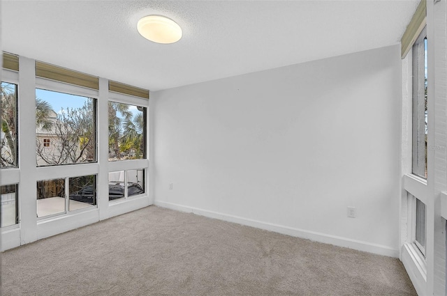 unfurnished room featuring carpet floors, a textured ceiling, and baseboards