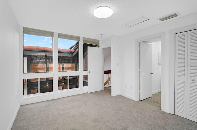 unfurnished bedroom with light carpet, a textured ceiling, and a closet