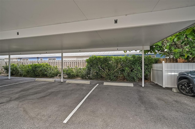 covered parking lot featuring fence