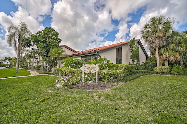 exterior space with stucco siding, a lawn, and a tiled roof