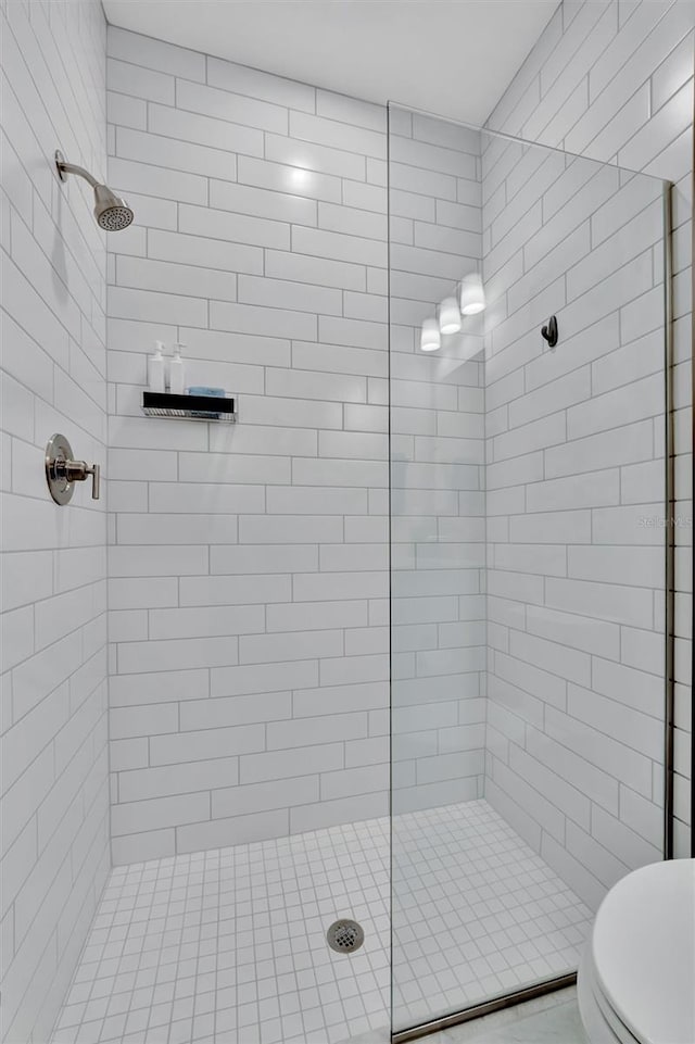 bathroom featuring a tile shower and toilet