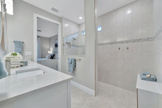 bathroom with a tile shower and vanity