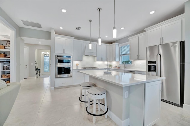 kitchen with a center island, white cabinetry, stainless steel appliances, sink, and backsplash