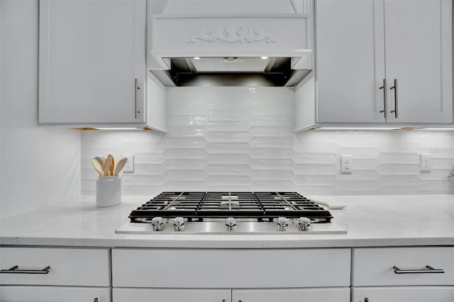 kitchen featuring decorative backsplash, light stone counters, stainless steel gas cooktop, and custom exhaust hood