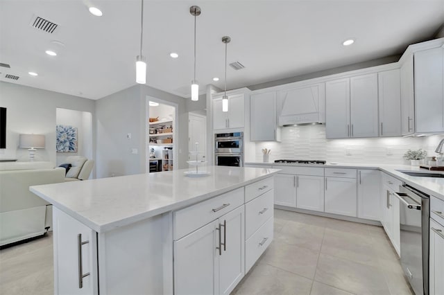 kitchen with custom exhaust hood, decorative backsplash, white cabinets, pendant lighting, and stainless steel appliances