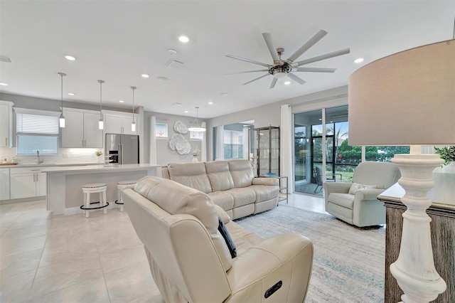 living room with ceiling fan, sink, and light tile patterned flooring