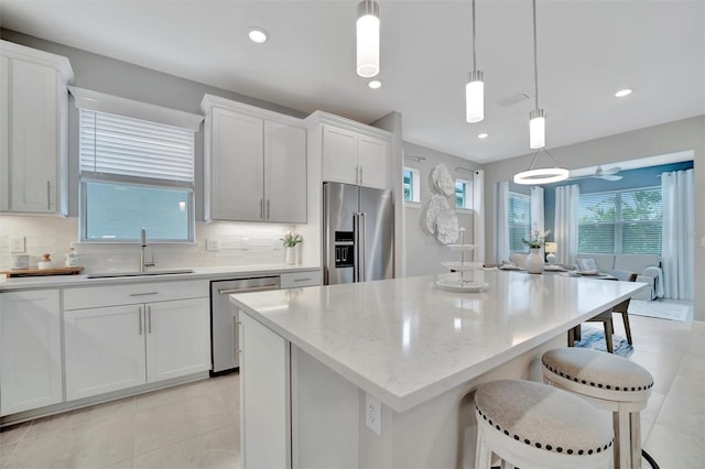 kitchen featuring decorative light fixtures, sink, white cabinets, and appliances with stainless steel finishes