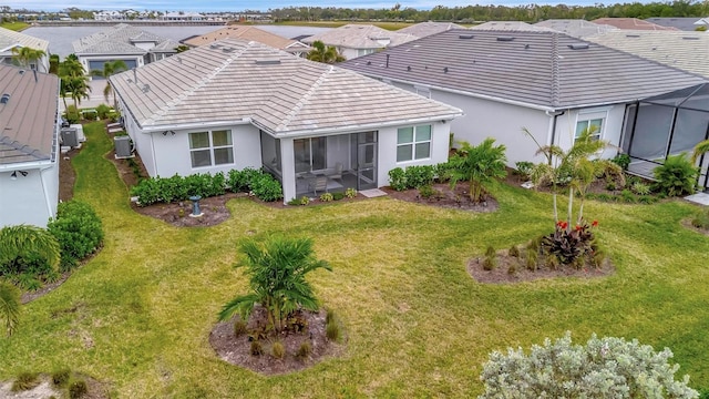 back of property with a sunroom, a lawn, and central air condition unit