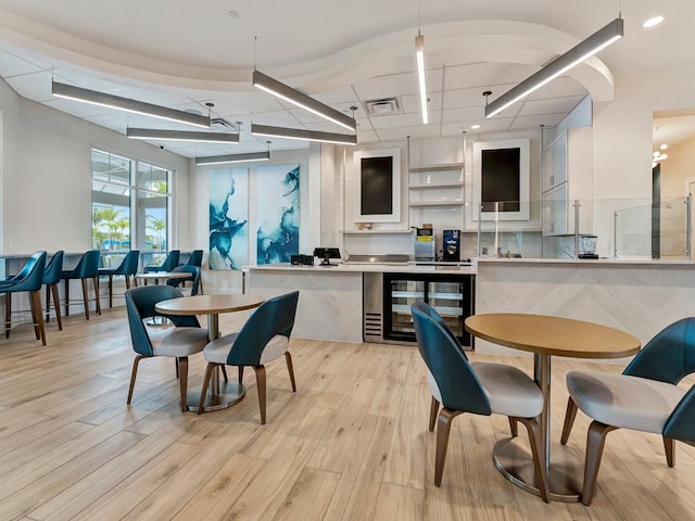 interior space featuring decorative light fixtures, light hardwood / wood-style floors, and white cabinetry