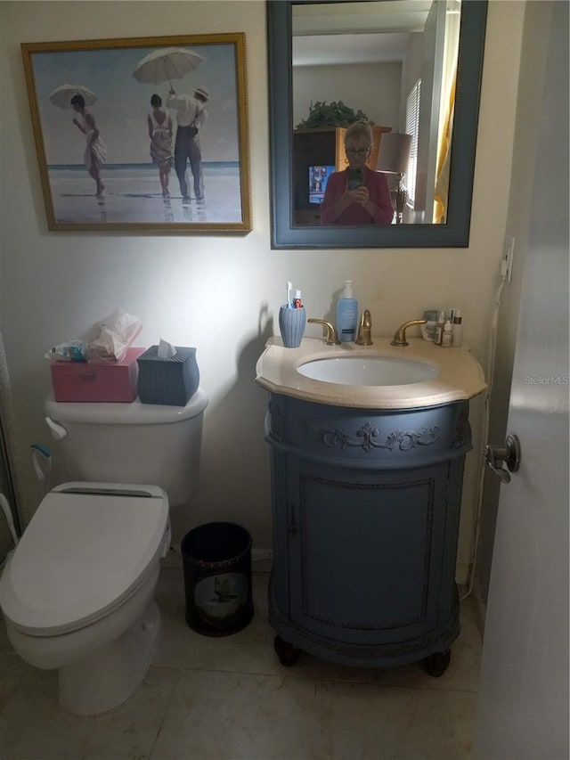 bathroom with toilet, vanity, and tile patterned flooring