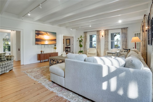 living room with light wood-type flooring, beam ceiling, and track lighting