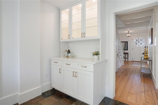 bar with white cabinets and dark hardwood / wood-style flooring