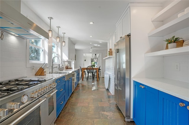 kitchen with decorative light fixtures, tasteful backsplash, wall chimney range hood, blue cabinetry, and high quality appliances