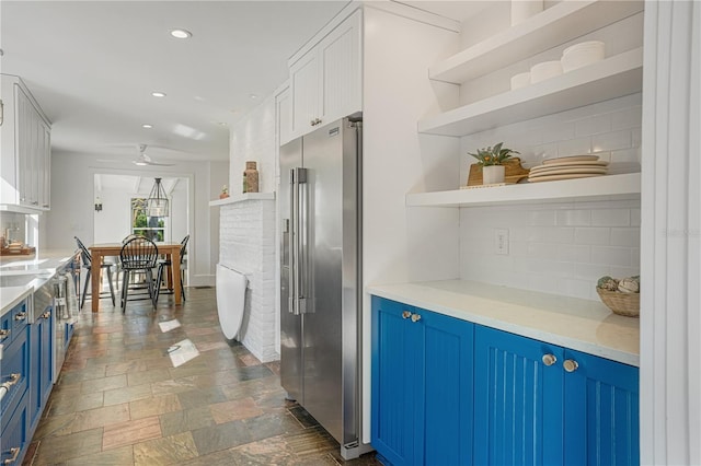 kitchen featuring white cabinetry, ceiling fan, tasteful backsplash, blue cabinetry, and high end refrigerator