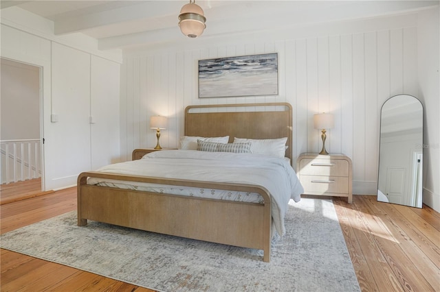 bedroom with beamed ceiling and light hardwood / wood-style flooring