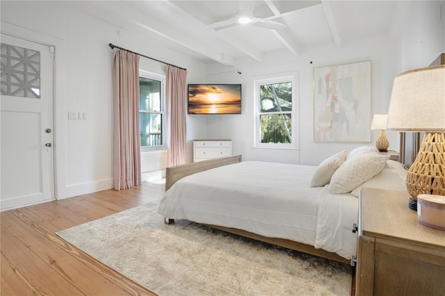 bedroom featuring ceiling fan, light hardwood / wood-style flooring, and beam ceiling