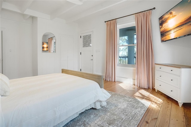 bedroom with beam ceiling and light wood-type flooring