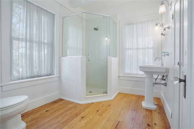 bathroom with toilet, an enclosed shower, and wood-type flooring