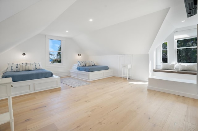 bedroom featuring light hardwood / wood-style floors, vaulted ceiling, and multiple windows