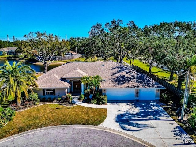 ranch-style home with a garage, a water view, and a front yard