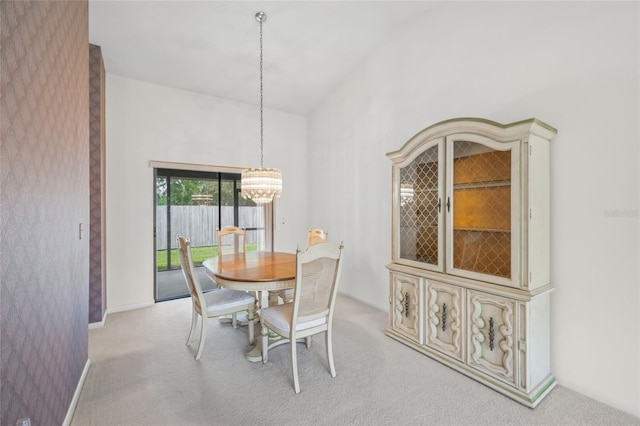 dining area with a notable chandelier, light colored carpet, and a high ceiling