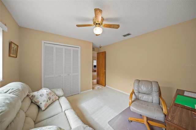 sitting room with ceiling fan, light colored carpet, and a textured ceiling