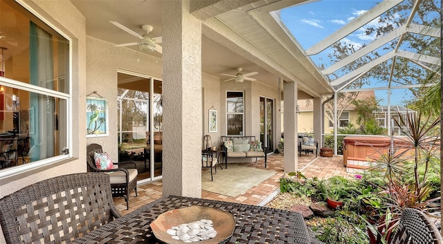 view of patio / terrace featuring ceiling fan, a lanai, a hot tub, and an outdoor living space