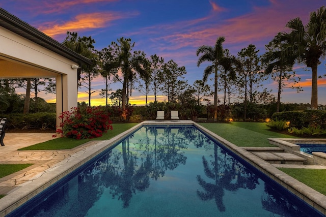 pool at dusk with a yard and a patio