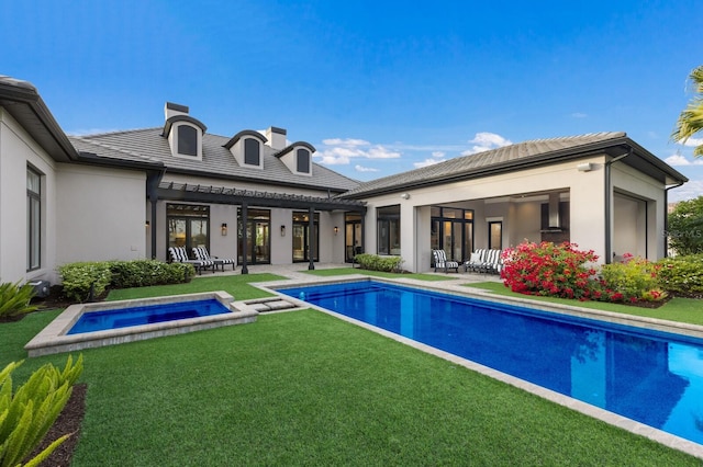 rear view of property featuring a patio, a swimming pool with hot tub, and a yard