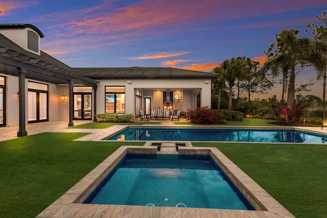 pool at dusk featuring a patio area and a yard