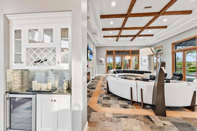 living room featuring coffered ceiling, beamed ceiling, bar area, and wine cooler