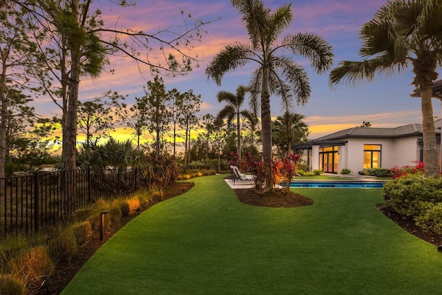 yard at dusk with a fenced in pool