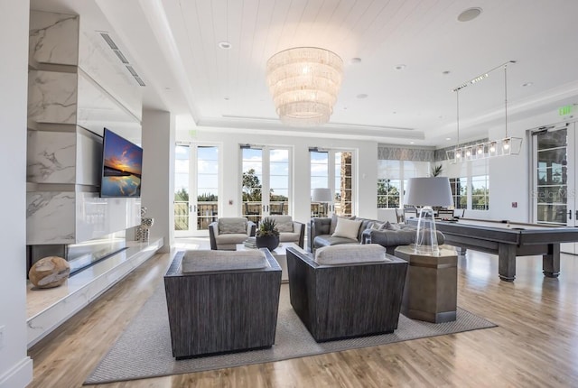 living room with wooden ceiling, a healthy amount of sunlight, a raised ceiling, and light wood-type flooring