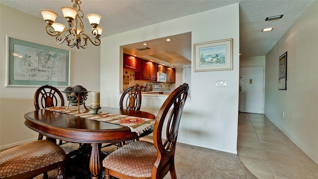 tiled dining space with a textured ceiling and a notable chandelier