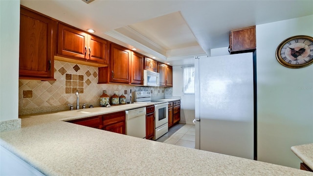 kitchen with backsplash, light tile patterned flooring, white appliances, and sink