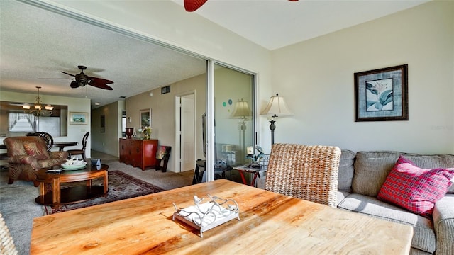 living room with carpet, ceiling fan, and a textured ceiling