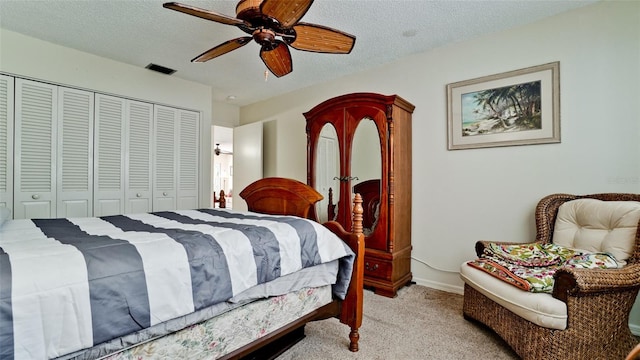 bedroom with a textured ceiling, a closet, ceiling fan, and light colored carpet