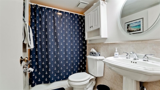 bathroom with curtained shower, sink, tile walls, and toilet