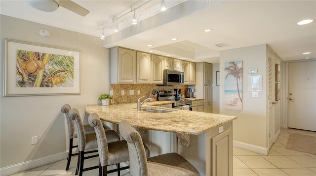 kitchen with appliances with stainless steel finishes, a sink, light tile patterned floors, decorative backsplash, and recessed lighting