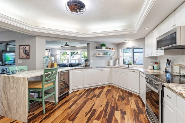 kitchen with white cabinetry, sink, stainless steel appliances, dark hardwood / wood-style flooring, and backsplash