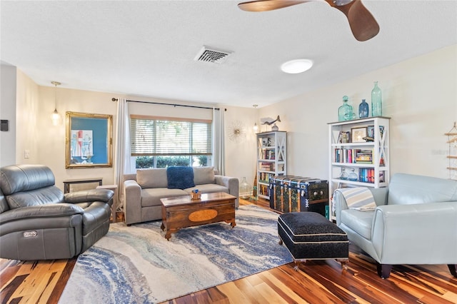 living room with hardwood / wood-style floors, a textured ceiling, and ceiling fan