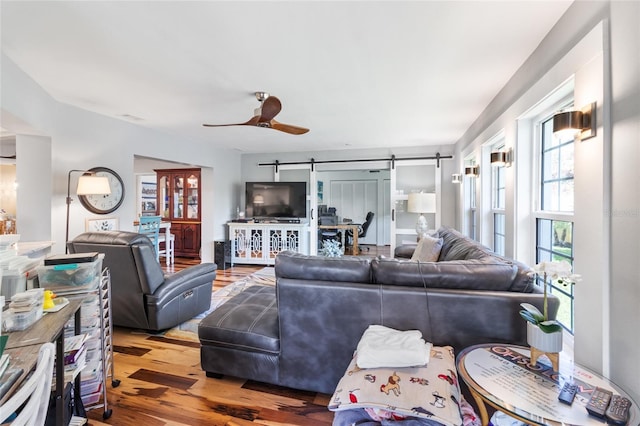 living room featuring hardwood / wood-style floors, a barn door, and ceiling fan